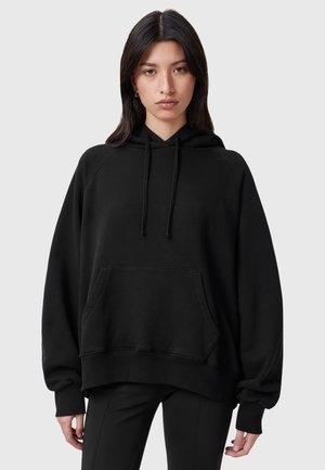 Sudadera negra de gran tamaño hecha de tela suave, con un bolsillo frontal, capucha con cordón y puños acanalados. Textura suave y corte relajado.
