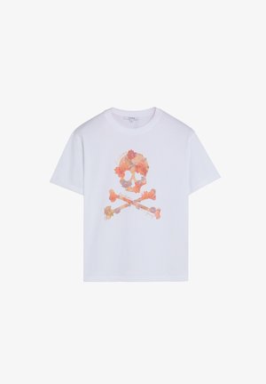 Camiseta blanca de manga corta con un diseño de calavera y huesos cruzados floral en tonos de naranja y rosa en el frente.