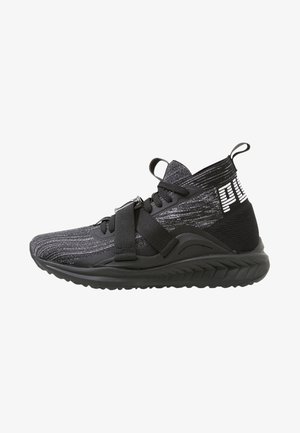 Baskets de sport noires et grises avec un texte blanc sur le talon, une semelle épaisse, des lacets et une sangle réglable sur le dessus.
