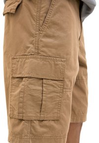 Tarnfarbene Cargo-Shorts mit mehreren großen Taschen, einer weichen Stofftextur und sichtbaren Nahtdetails. Geeignet für legere Bekleidung.