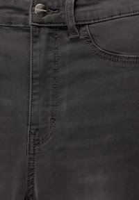 Gros plan sur un jean en denim gris foncé montrant un bouton en métal avec le texte « Pull&Bear », une passoire de ceinture, le bord supérieur et le détail de la poche avant cousue.