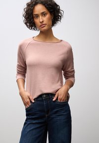 Helles rosa Langarm-T-Shirt mit weitem Halsausschnitt und gerippten B�ündchen, kombiniert mit dunkelblauen Jeans im klassischen Schnitt und feinen Nähten.