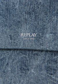 Tela vaquera en varios tonos de azul con un patrón texturizado. Presenta el logo "REPLAY" y el texto "SINCE 1981" en blanco.
