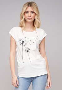 T-shirt en coton blanc avec des manches retroussées, affichant un imprimé de pissenlit noir, coupe courte et texture douce.