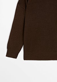 Manche et torse de pull en maille marron avec poignets et ourlet côtelés sur fond blanc.