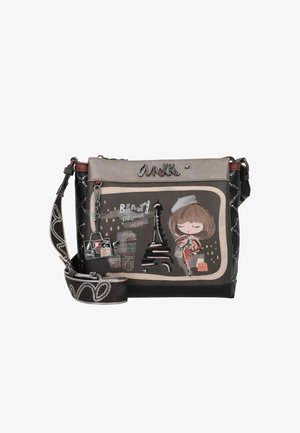 Bolso bandolera hecho de material sintético negro con ilustración de la Torre Eiffel, correa ornamentada y charms decorativos.