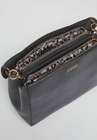 Borsa a tracolla nera in pelle con accessori dorati, dotata di diversi scomparti con zip e rivestimento leopardato. Forma rettangolare, texture liscia.