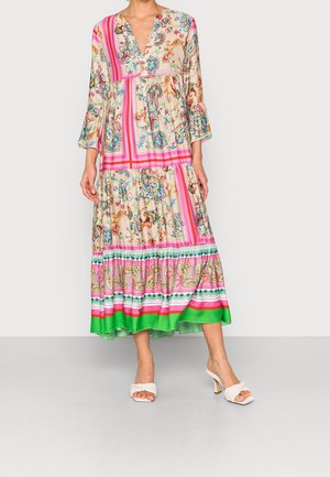 Abito lungo con motivo floreale e paisley con pannelli rosa, verdi e beige, maniche svasate e sandali bianchi intrecciati con tacco.