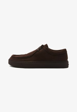 Scarpa slip-on in suede marrone con punta arrotondata, dettagli di cucitura e suola testurizzata. Branding sottile sul lato.