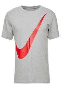 Světle šedé tričko s krátkým rukávem s velkým červeným logem Nike swoosh umístěným šikmo přes přední část.
