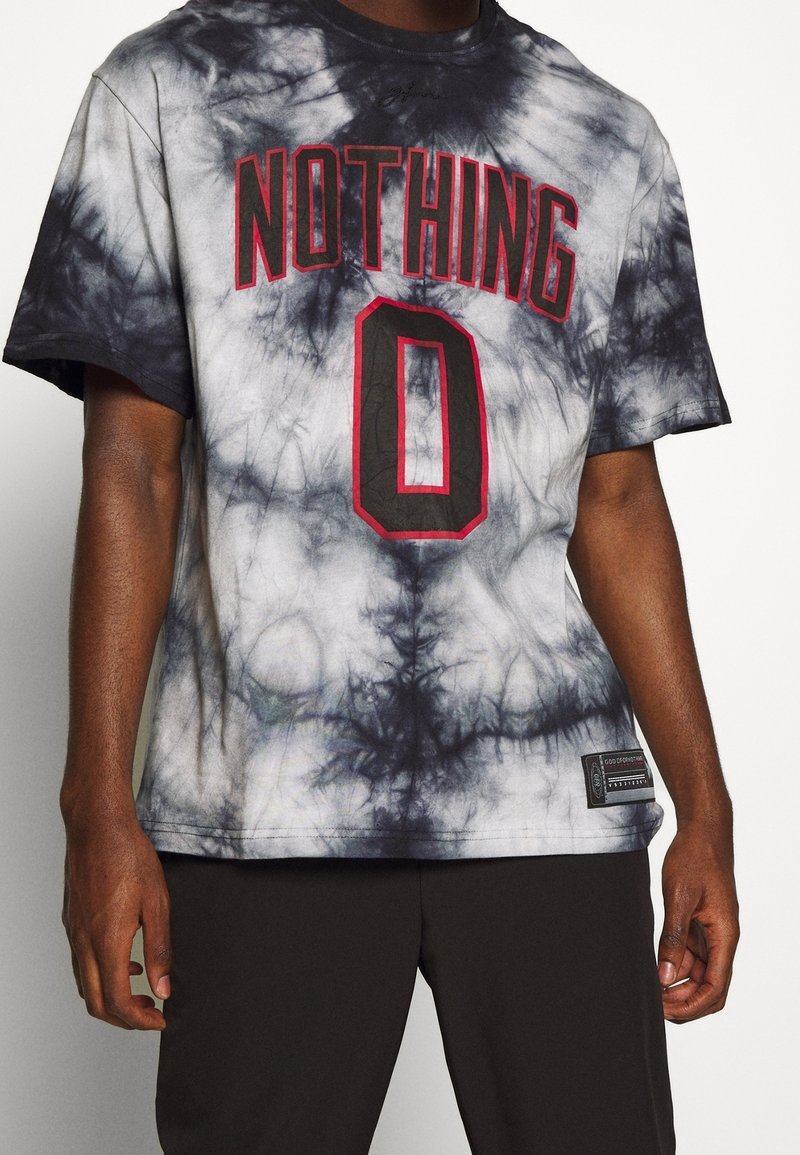 Camiseta de manga corta en tie-dye en blanco y negro, con la impresión en rojo de "NOTHING" y un "0" prominente en el frente, con tejido texturizado.