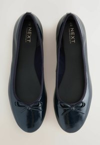 Ballerines en cuir verni bleu marine avec un bout arrondi, un bord élastique et un petit nœud à l'avant. Doublure intérieure douce.