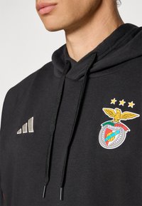 Fekete kapucnis pulóver, szürke hímzett Adidas logóval és egy színes Benfica címerrel arany kiemelésekkel, valamint húzható kapucnival.