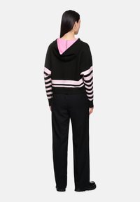 Black cropped hoodie with pink stripes on sleeves and lower hem. Paired with black trousers and black platform shoes. Smooth texture.