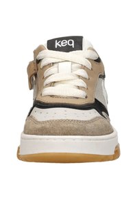Beige und weiße Sneaker aus strukturiertem Wildleder und Mesh, mit schwarzen Akzenten, auffälligen Schnürsenkeln und einer Gummisohle. Logo auf der Zunge. Vorderansicht.