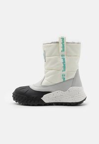 Bílé izolované boty s šedými akcenty, černou gumovou podrážkou a texturovaným svrškem. Obsahují logo Timberland a smyčkovou poutko.