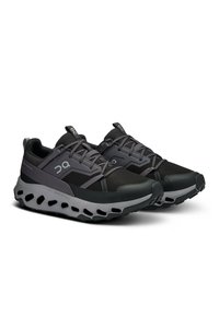 Schwarze und graue Sportschuhe mit einem Obermaterial aus Mesh, strukturiertem Material, gepolsterter Sohle und markanten Ausschnitten im Zwischensohlendesign.