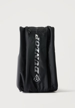 Schwarze Dunlop Sporttasche mit großem vertikalem Logo und Reißverschlusstaschen vor einfarbig hellem Hintergrund.
