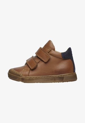 Bruine leren sneaker met dubbele klittenbandsluitingen, een gestructureerde rubberen zool en een blauwe suède accent op de hiel. Rond afgewerkte neus.