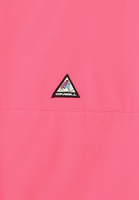 Felle roze jas met een driehoekige zwart-wit logopatch met een grafisch ontwerp. Gladde textuur; minimalistisch ontwerp zonder aanvullende patronen.