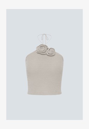 Beige gebreide haltertop met twee decoratieve spiraalvormige bloemen bij de halslijn en een dunne strikband aan de achterkant.