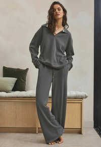 Gray, textured loungewear set featuring a loose-fit pullover and wide-leg pants, designed with a collar and drawstring waist.