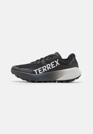 Black athletic shoe with mesh upper, bold "TERREX" branding, synthetic accents, and a contrasting gray sole. Designed for performance.