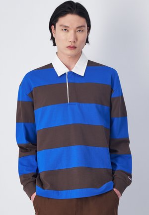 Polo a maniche lunghe a righe blu e marroni con colletto bianco, dotato di una patta con tre bottoni e un logo accentato sulla manica.