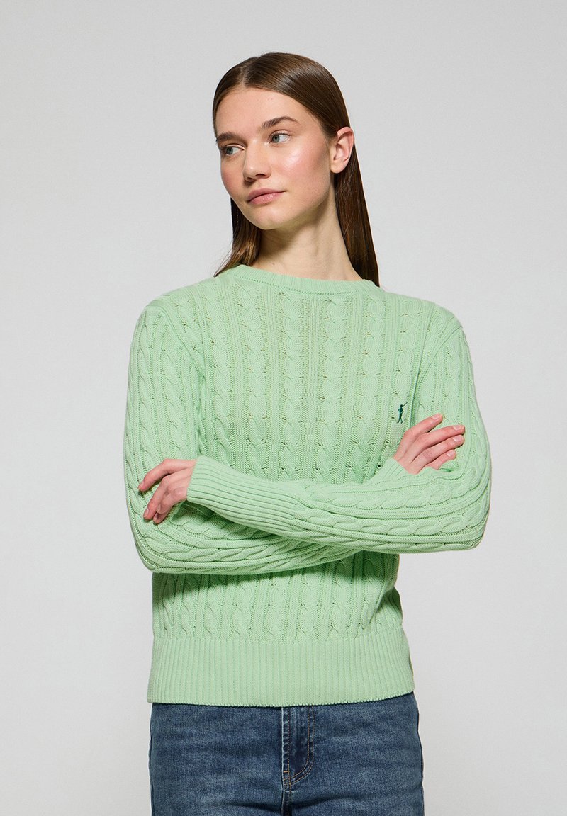 Mintgrön kabelstickad tröja med ribbade cuffs och nederkant, med en liten broderad logotyp på bröstet. Avslappnad passform, texturerad tyg.
