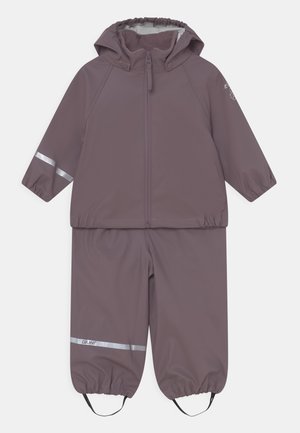 Costume de pluie violet en matériau imperméable, avec une veste zippée dotée d'une capuche et d'accents réfléchissants, ainsi que des poignets et un pantalon élastiques.