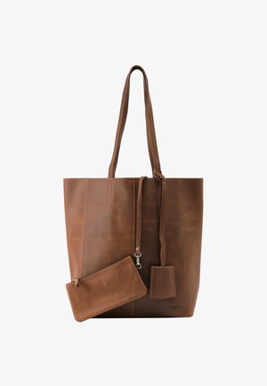 Bolso tote de cuero marrón con asas largas, un pequeño bolso desmontable y una etiqueta de cuero colgante sobre un fondo blanco.