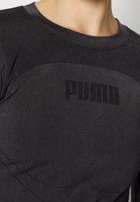 Svart långärmad sporttröja i stretchmaterial, med en figurnära design och texturerad panelering, samt en framträdande svart "PUMA"-logotyp.