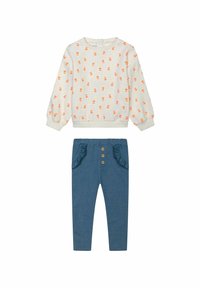 Dvojdielny outfit pozostávajúci z krémového svetra s oranžovými kvetinovými vzormi a modrých nohavíc s volánikmi a drevenými gombíkmi ako ozdobami.