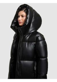 Giubbotto piumino nero con finitura lucida, cappuccio oversize, design trapuntato e grandi tasche frontali, dotato di chiusura a zip e dettagli con logo.