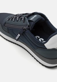 Scarpe da tennis da uomo in navy con tomaia in tessuto testurizzato, zip integrata e accenti del logo bianchi. Suola in gomma nera con intersuola grigia.
