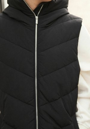 Czarna pikowana kamizelka z kapturem, z przeszywanym wzorem, zapinana na zamek z przodu i z bocznymi kieszeniami. Gładka tekstura i lekki materiał.
