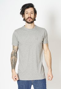 Grå bomulds t-shirt med korte ærmer og rund halsudskæring, der har en glat tekstur. Båret med blå denim jeans.