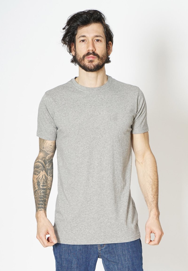 Grå bomulds t-shirt med korte ærmer og rund halsudskæring, der har en glat tekstur. Båret med blå denim jeans.