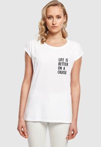 Hvid casual t-shirt med opsmøgede ærmer, med sort tekst der står "LIVET ER BEDRE PÅ KRYDSTOGT" på venstre side.