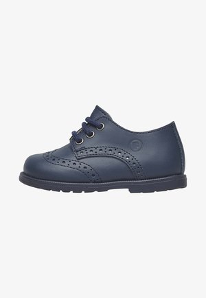 Navy blue leather child's brogue shoe with wingtip perforations, three eyelets with navy laces, and rubber sole.
