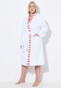 Accappatoio bianco in spugna con un bordo multicolore a righe lungo il colletto, dotato di maniche lunghe e una vita regolabile con cinturino. Include una tasca laterale.