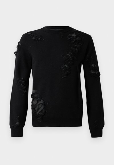 Fekete pulóver hosszú ujjal, megtört anyagú részletekkel és texturált foltokkal. Kerek nyakkivágás és puha kötött anyag.