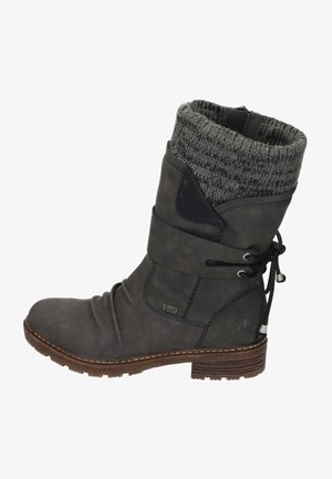 Bottine en cuir gris avec une tige tricotée grise, des lacets sur le côté et une semelle texturée. Elle présente un petit logo sur le côté et des détails de couture.