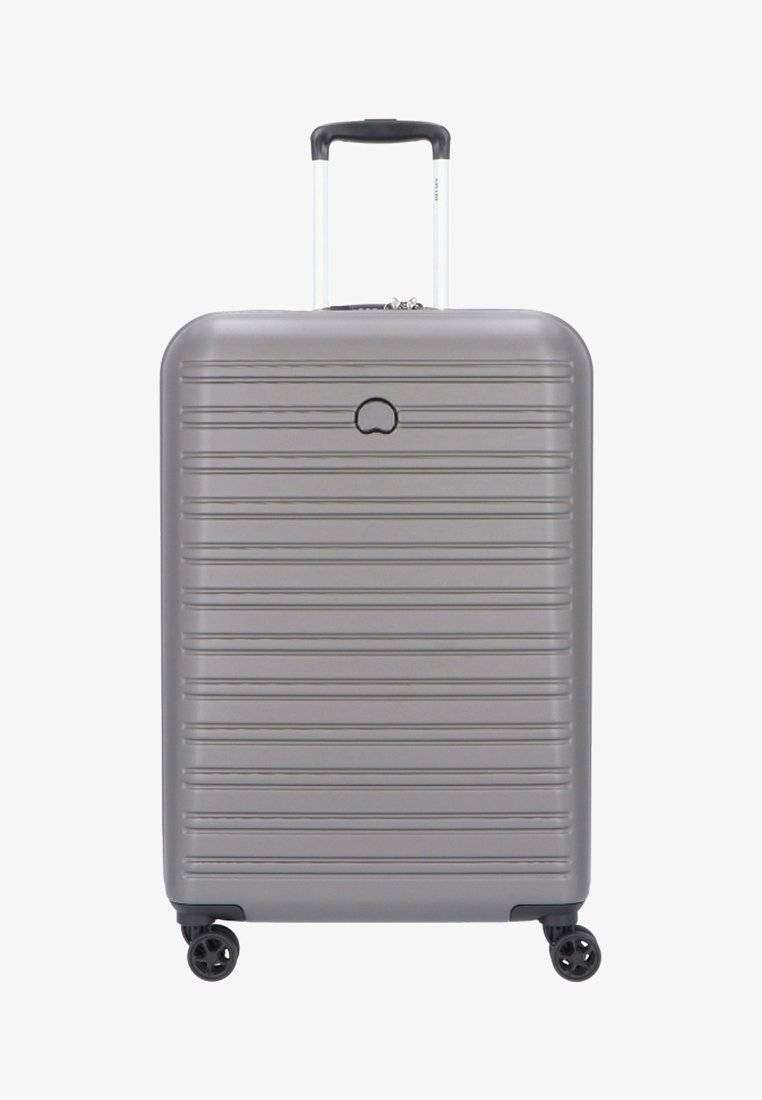 Grijze hard-shell bagage met verticale groeven, een uitschuifbare handgreep, vier wielen en een logo centraal net bovenaan.