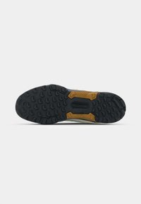 Semelle extérieure en caoutchouc noir avec un motif texturé, mise en valeur par un accent marron. Bords renforcés pour une durabilité accrue. Éléments de traction améliorant l'adhérence.
