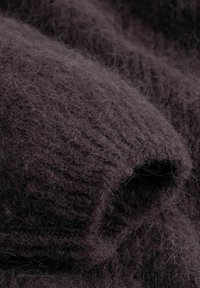 Close-up of soft, fuzzy dark brown knitted fabric showing detailed texture and fibers.