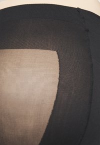Sorte, gjennomsiktige strømpebukser med en solid beige panel i midten. Har en strukturert strikk og en elastisk midje. Ingen synlige maskinvare.