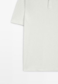 Polo a maniche corte grigio chiaro con motivo a maglia strutturata, dotata di colletto con patta a quarto e vestibilità rilassata.