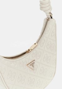 Borsa bianca trapuntata con una cerniera dorata, dotata di una placca con logo e una maniglia avvolta. Texture liscia con motivi floreali cuciti.