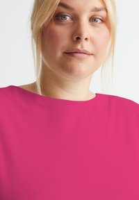 Rosa kurzärmliges Oberteil mit weitem Ausschnitt, das eine glatte Textur und ein sauberes, minimalistisches Design aufweist. Keine sichtbaren Muster oder Akzente.